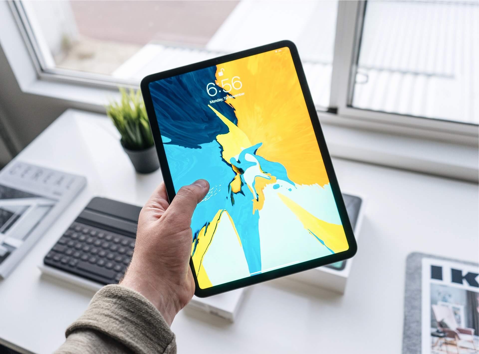 Person holding an iPad Pro over a white desk
